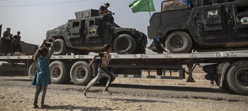 Kinderen zwaaien naar gevechtsvoertuigen van het Iraakse leger, onderweg naar Mosul. Foto: Sam Tarling/Oxfam