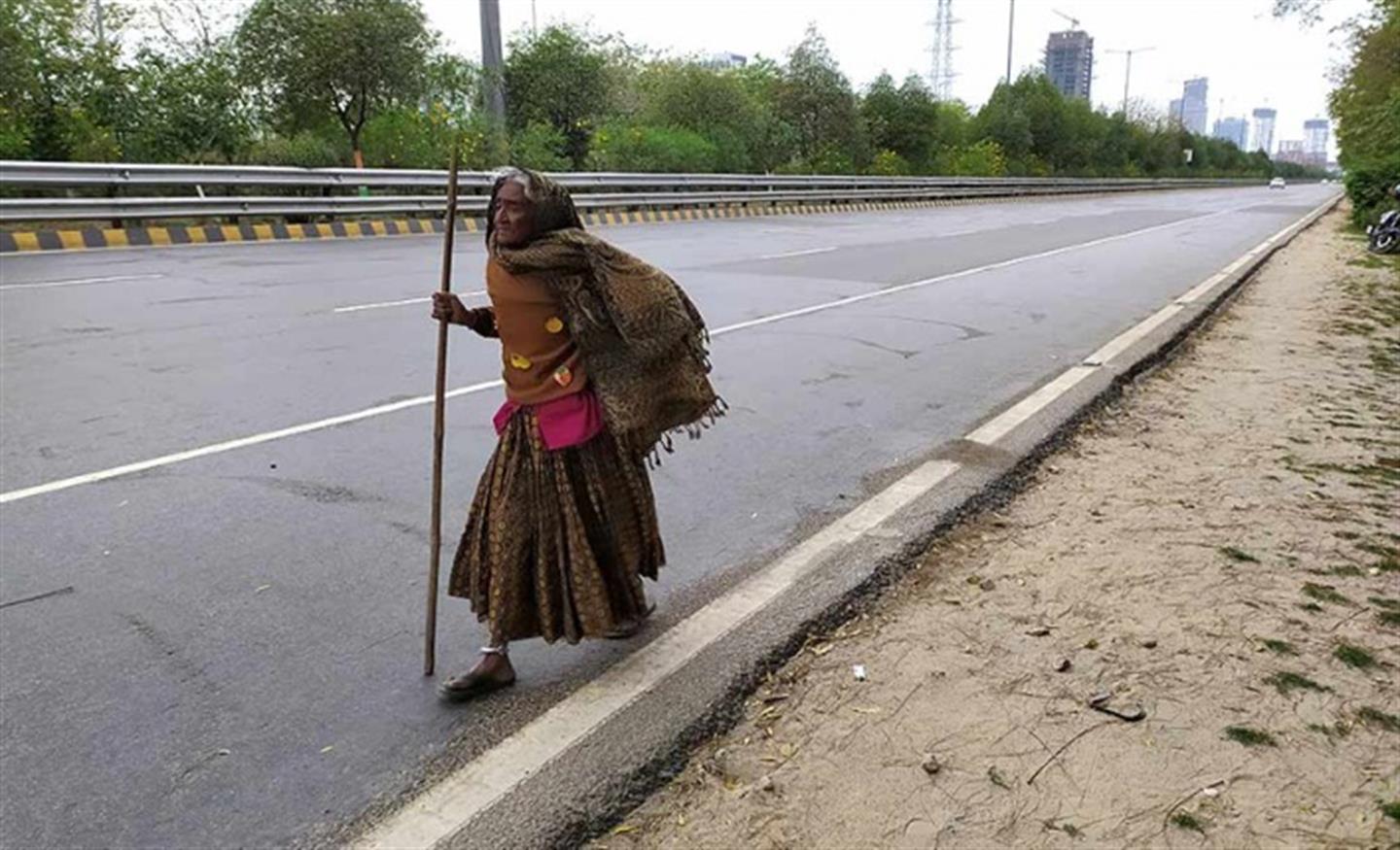 Een vrouw loopt over de lege straat naar haar dorp