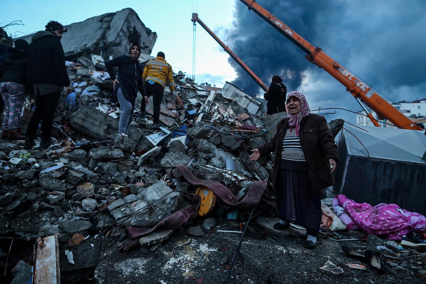 Een vrouw staat tussen de puin veroorzaakt door de aardbeving