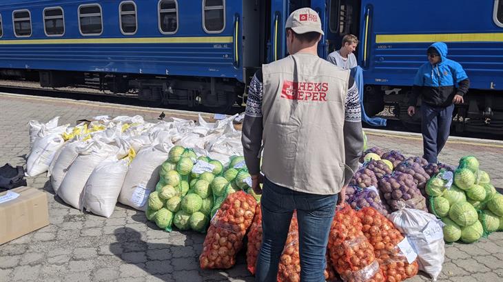 Hulpverlener van een Oxfam-partner staat naast zakken vol eten
