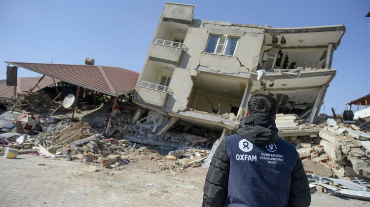 Een Oxfam-medewerker tussen de puinhoop van de aardbeving