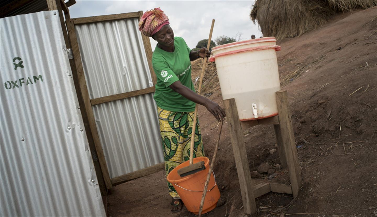 Een Oxfam-medewerker maakt toiletten schoon in een vluchtelingenkamp